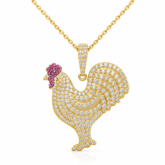A gold-tone rooster pendant necklace paved with clear cubic zirconia stones, featuring a small crown of pink gemstones on the head, shown on a white background.
