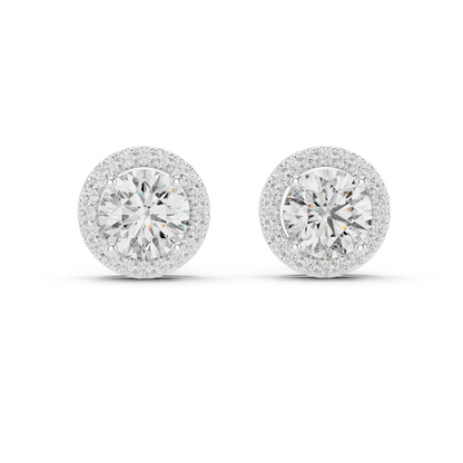 A pair of round halo stud earrings with brilliant-cut center stones surrounded by a halo of smaller stones, set in a silver-toned metal on a white background.